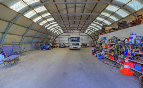 Ensemble immobilier comprenant une maison, deux entrepôts et un vaste terrain